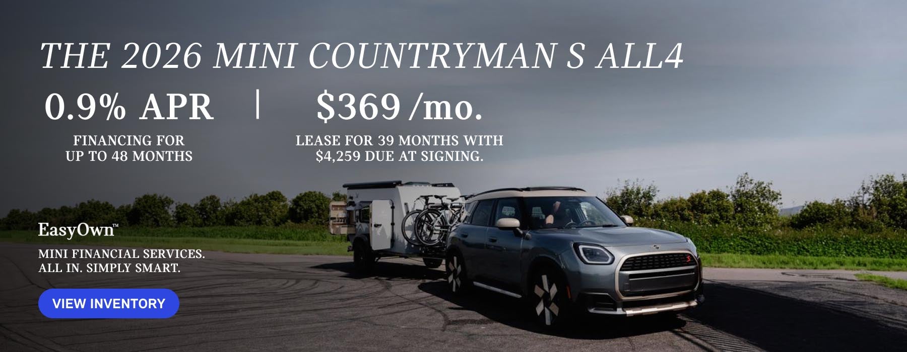 Un MINI Countryman gris aparcado con bicicletas y un remolque a cuestas.