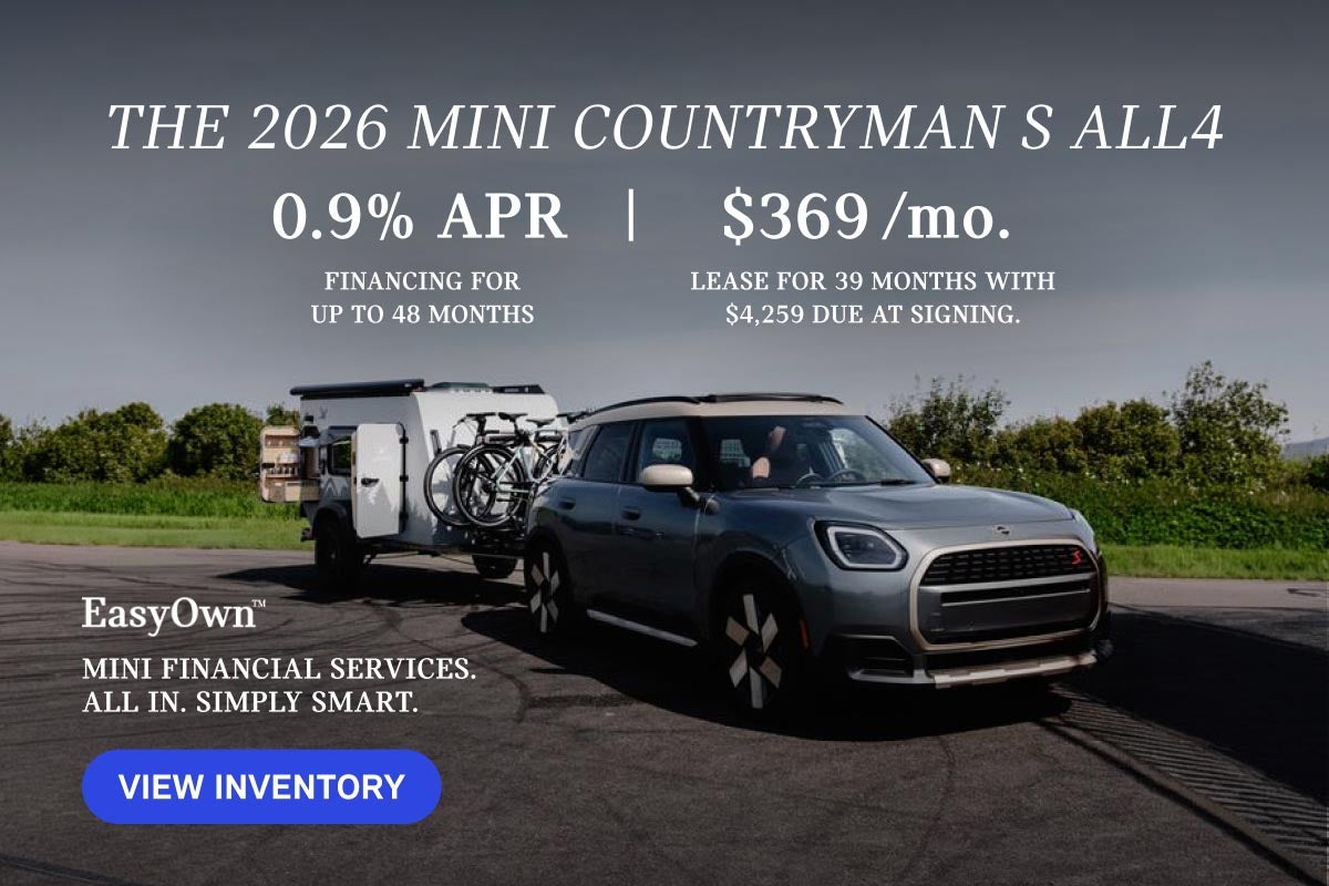 Un MINI Countryman gris aparcado con bicicletas y un remolque a cuestas.