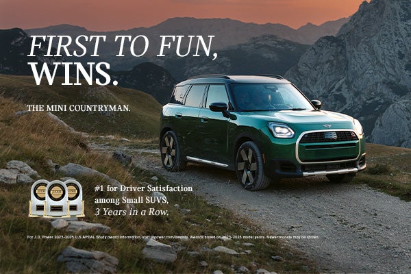 Vista lateral del lado del acompañante de un MINI Countryman verde circulando por una carretera de montaña.