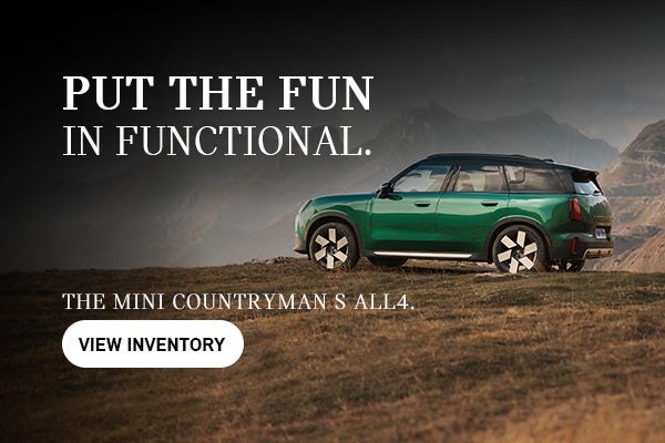 Un MINI Countryman S ALL4 verde aparcado en un mirador de montaña cubierto de hierba, con picos escarpados al fondo. El texto promocional dice: