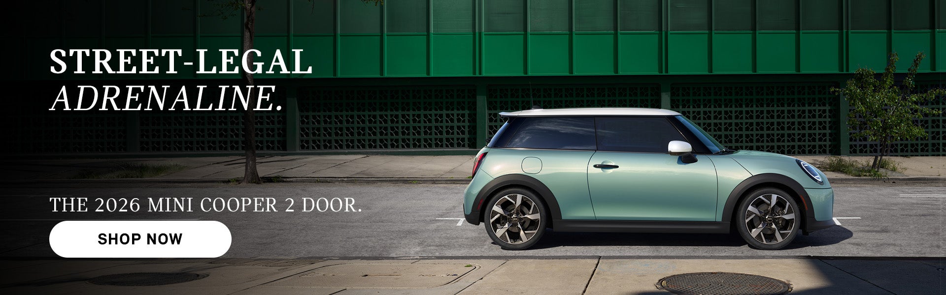 MINI Cooper de dos puertas de color verde menta aparcado en una calle de la ciudad con edificios al fondo, junto a un texto publicitario que promociona el modelo de 2026