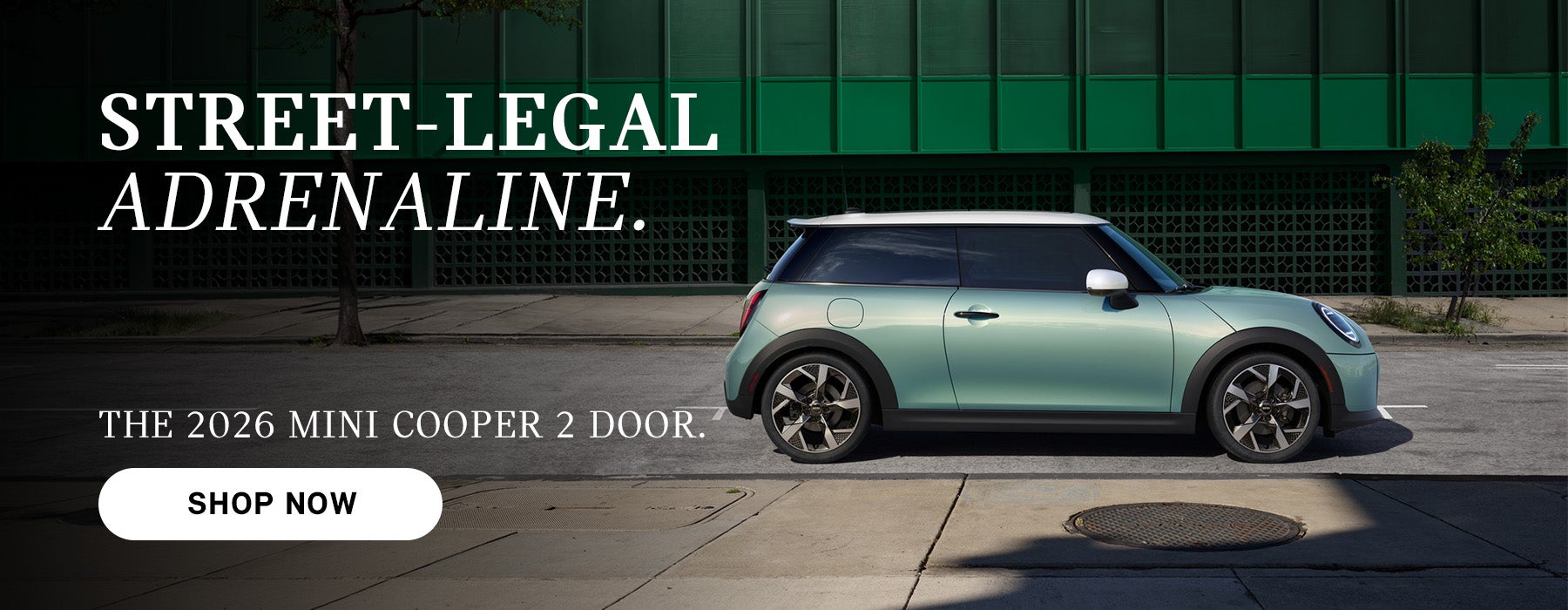 MINI Cooper de dos puertas de color verde menta aparcado en una calle de la ciudad con edificios al fondo, junto a un texto publicitario que promociona el modelo de 2026