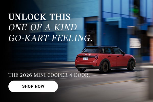 Un MINI Cooper rojo de cuatro puertas circulando por una calle de la ciudad, con un efecto de desenfoque de movimiento al fondo y un texto publicitario que promociona el modelo de 2026.