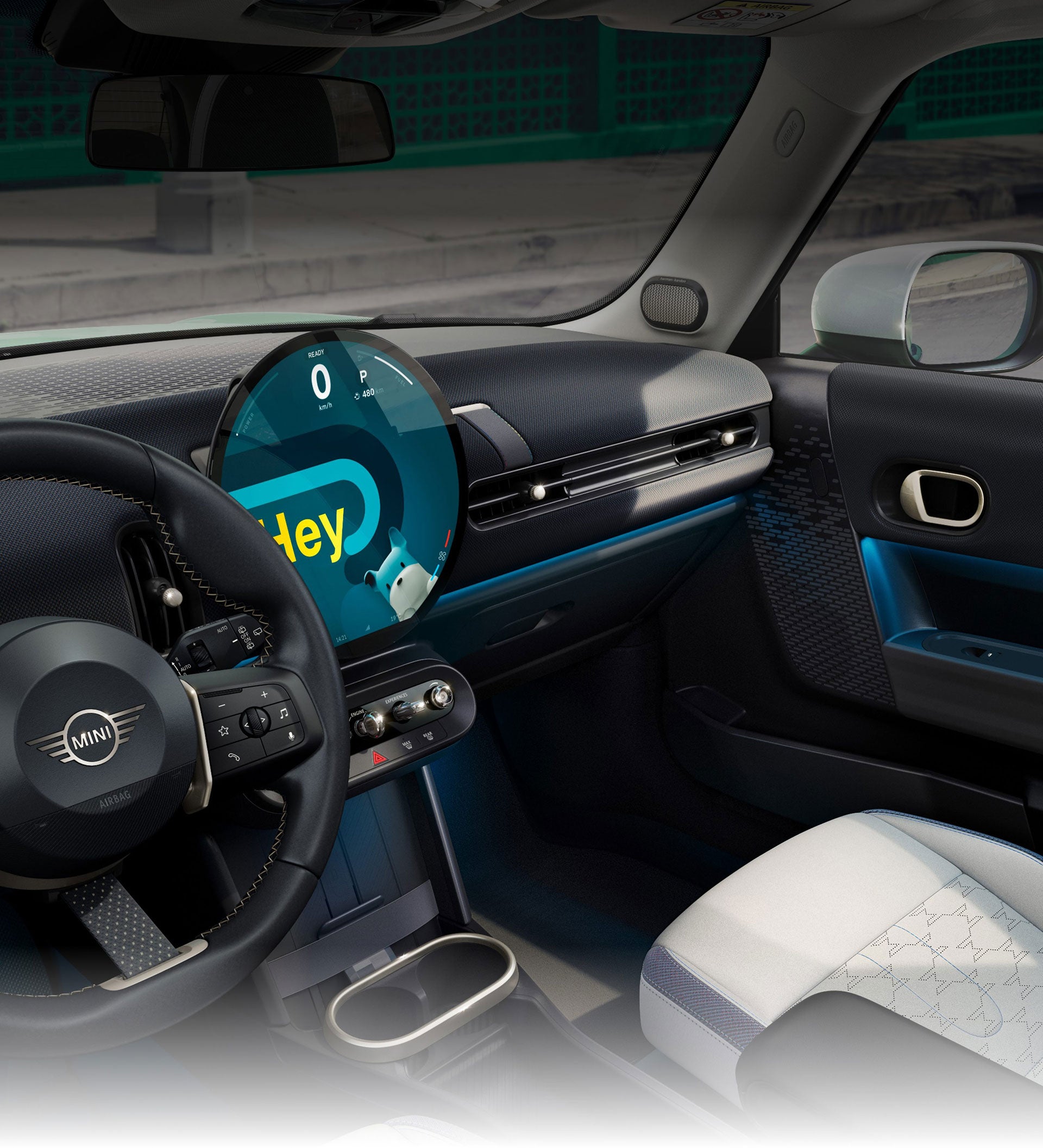 Una vista en ángulo del interior del Mini Cooper Hardtop 2 Puertas tomada desde el lado del acompañante en la que se aprecian los asientos deportivos delanteros con el cielo azul y los árboles por las ventanillas.