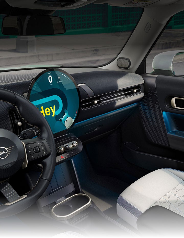 Una vista en ángulo del interior del Mini Cooper Hardtop 2 Puertas tomada desde el lado del acompañante en la que se aprecian los asientos deportivos delanteros con el cielo azul y los árboles por las ventanillas.