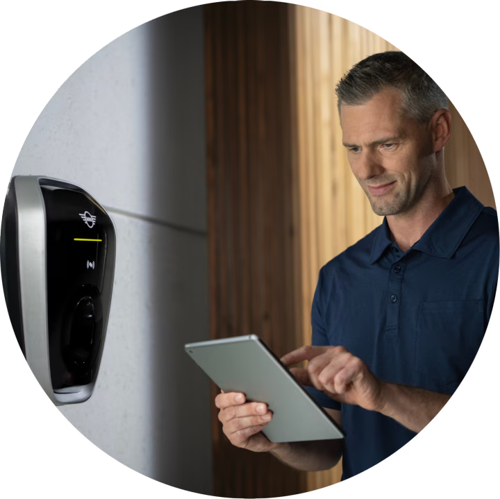 Un hombre mira un iPad mientras está delante de un cargador doméstico.