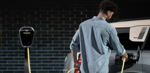 Un hombre carga su MINI Countryman SE ALL4 de 2025 contra un muro de ladrillos.