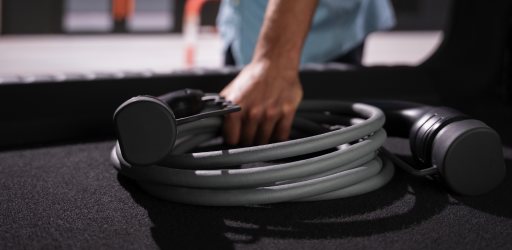 Una persona coge un cargador de vehículo eléctrico de su maletero.