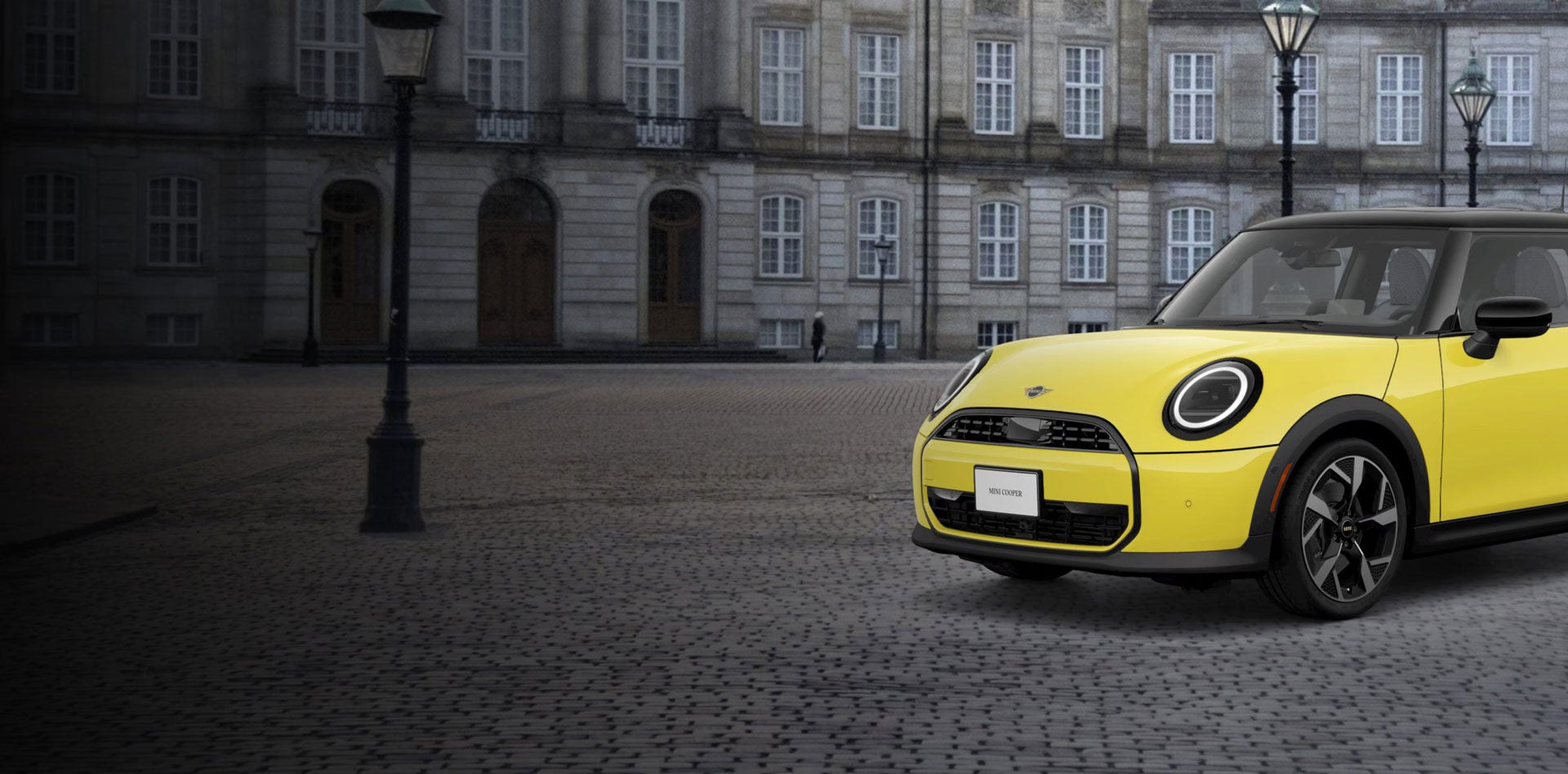 ¾ Vista lateral delantera de un MINI Cooper Oxford Edition aparcado en una calle de ladrillo delante de un edificio.