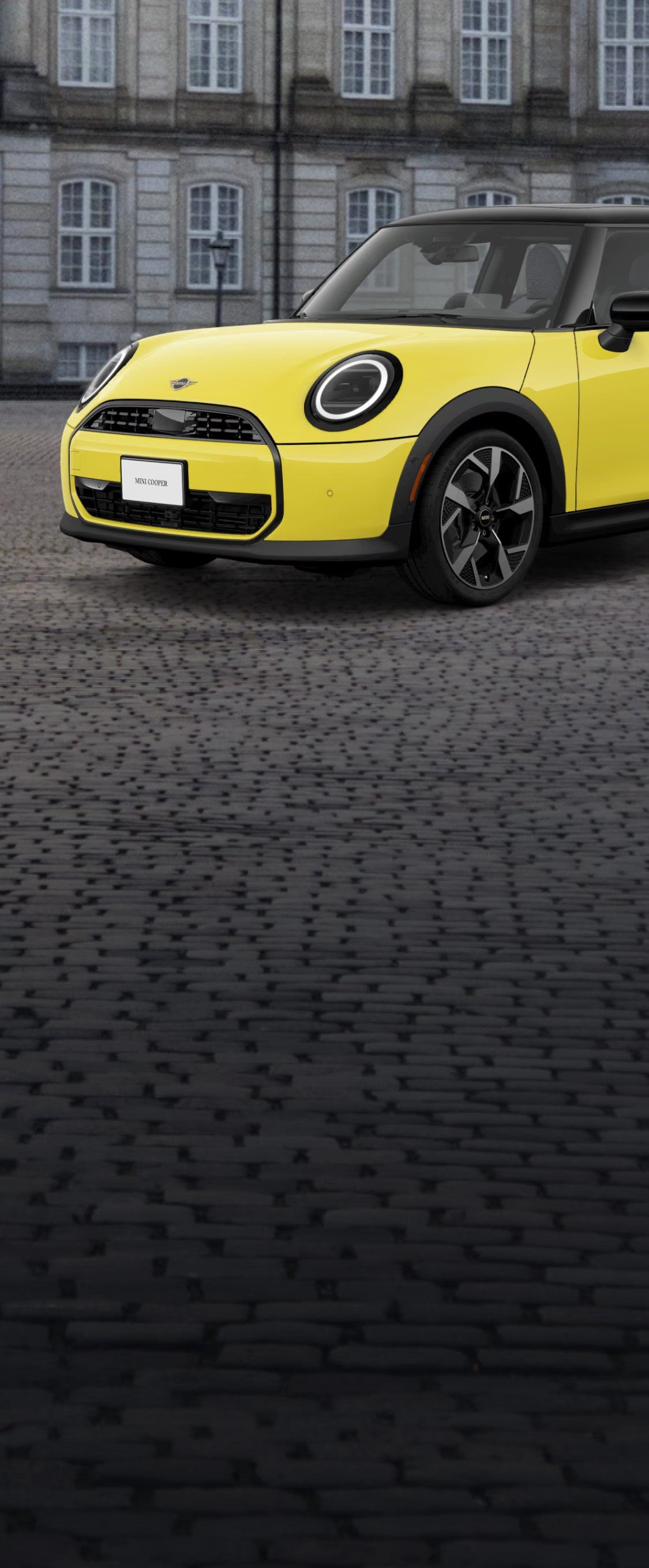 ¾ Vista lateral delantera de un MINI Cooper Oxford Edition aparcado en una calle de ladrillo delante de un edificio.