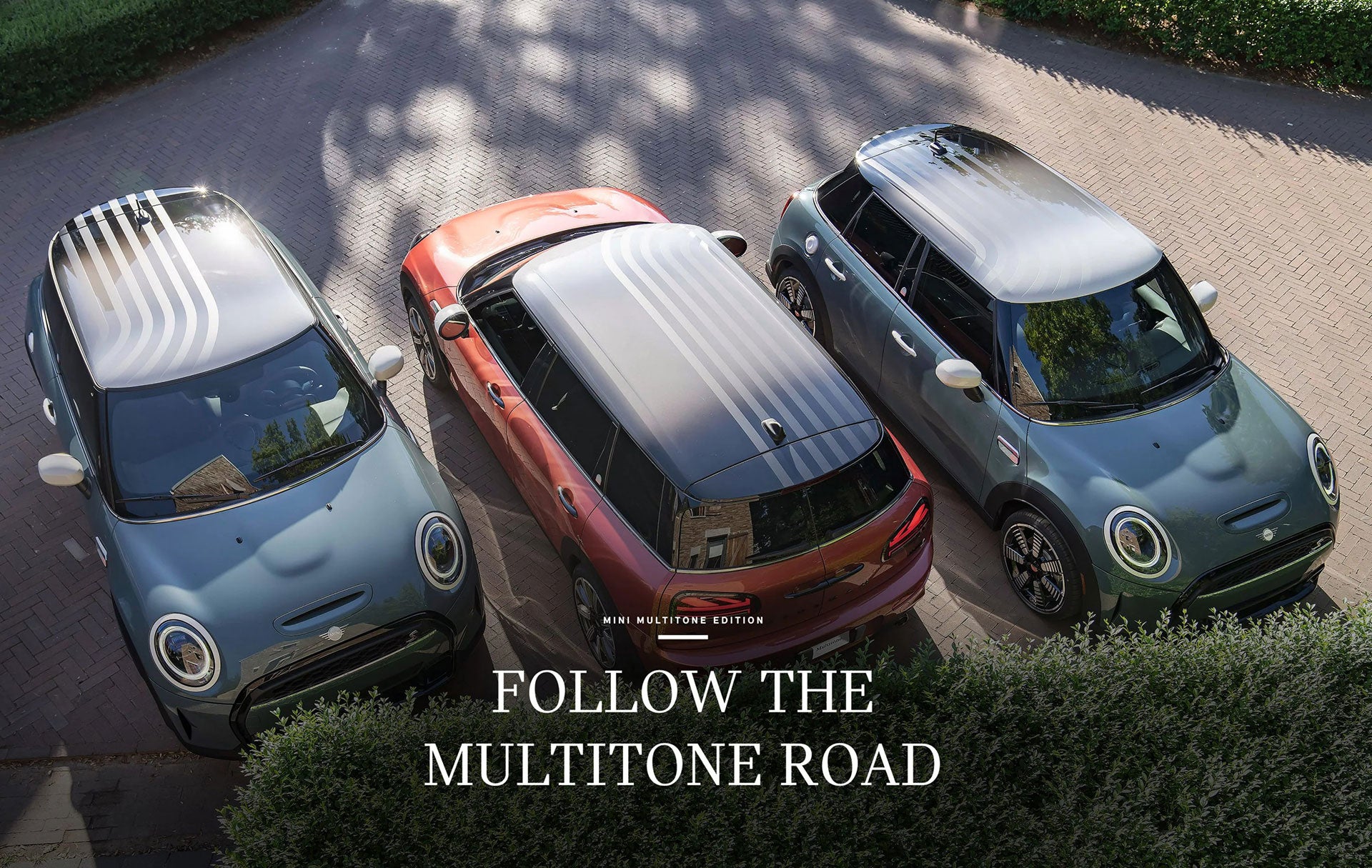 Tres MINI Multitone Edition en verde salvia y rojo coral aparcados uno al lado del otro sobre una superficie de ladrillo.