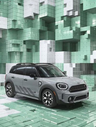 Vista superior de tres cuartos de un MINI Countryman Untamed Edition, mostrando sus detalles exteriores en negro piano, y el techo y las carcasas de los retrovisores en negro, en un mundo CGI formado por cajas en 3D, tipo Tetris.