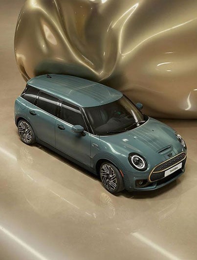 Vista superior de tres cuartos de los refinados detalles de latón delanteros y traseros de un MINI Clubman Untold Edition, que tiene un gigantesco globo de latón CGI, inflable y brillante, que sale del lateral del coche.