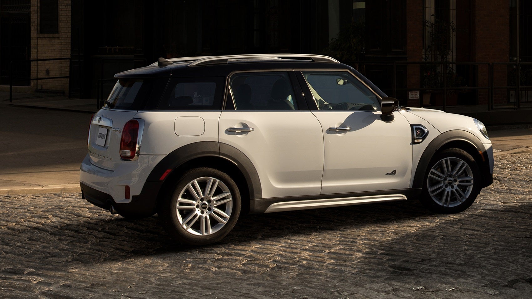 Un MINI Countryman blanco en un camino empedrado en el casco antiguo de una ciudad